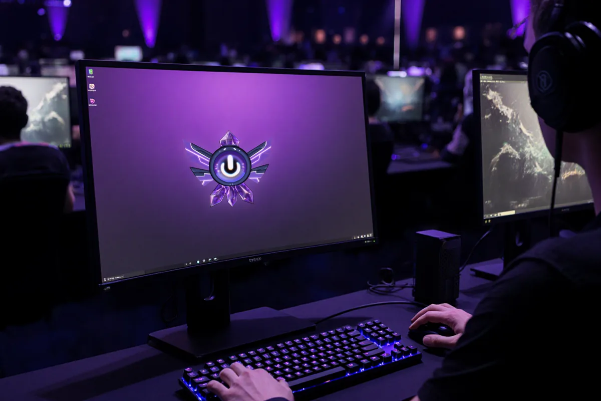 Rangée de postes PC gaming allumés dans une salle sombre, claviers rétroéclairés et joueurs installés à leur poste